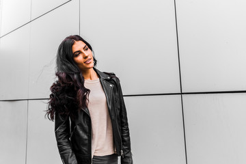 young latin woman walking with happy emotion on grey wall