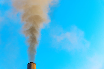 Black smoke rise from smoking pipe against blue sky.