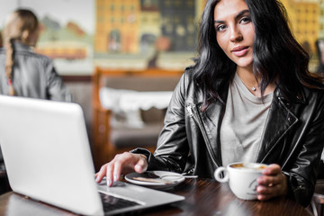 Young pretty spanish woman in cafe in city centre with tablet laptop