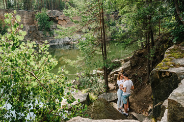 Fototapeta na wymiar Young couple hugging a stone near the lake. A man and a woman stand against the background of the rocks. Top view. Nature. autumn. full length. looking at each other.