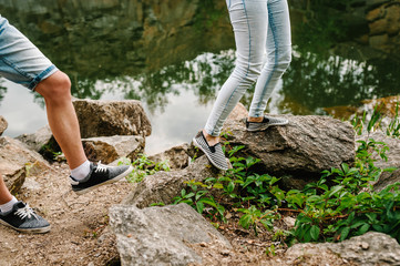 Legs young couple run on stone near lake. Down view. lower half Man's and woman's legs going on background of rocks. Landscape of an old industrial granite quarry. Close up