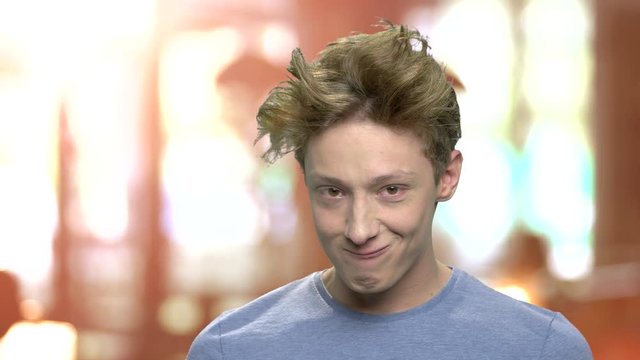 Funny teen boy grimacing. Teenage boy making funny faces. Funny facial expression. Brown blurry background.