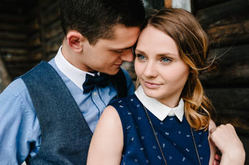 A man hugs back a tender woman. upper half. looking down. on the background nature. close up. Young lovers couple standing near an old wooden stylish house.