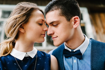 A face of young couple kissing near a wooden old house on the background with windows. Close up. headshot, half length.