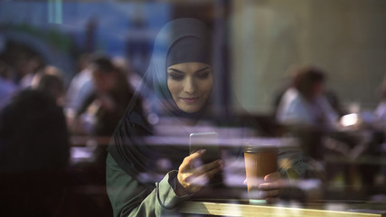 Attractive lady in hijab chatting on phone, free to communicate with friends