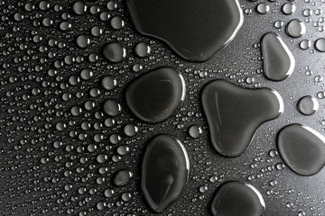 Droplets of water on a black, matte background illuminated with a delicate light.