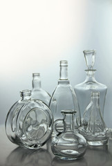 Empty glass bottles. Transparent forms for cold drinks, randomly presented and isolated on a gray background.