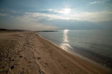 calm sea beach in summer with large rocks and wooden poles from old breakewater in the sea