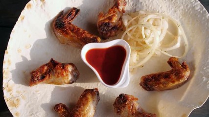 Chicken Kebab with onions on pita close up. Rotates on a wooden background. Top view.