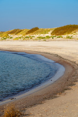 calm sea beach in summer with large rocks and wooden poles from old breakewater in the sea