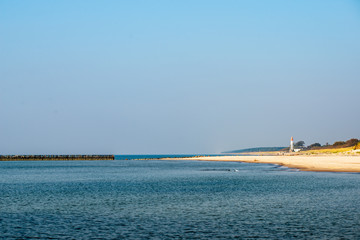 calm sea beach in summer with large rocks and wooden poles from old breakewater in the sea