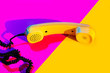 Retro vintage phone handset yellow pink red purple plastic orange disko background old style shadow...