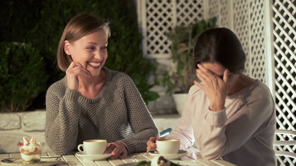 Joyful female friends discussing gossips, sitting cafe table laughing, leisure