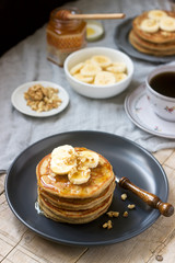 Pancakes with banana, nuts and honey, served with tea. Rustic style.