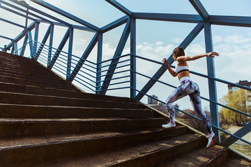 Obraz na płótnie Canvas Sporty woman who is running in an urban setting over a bridge