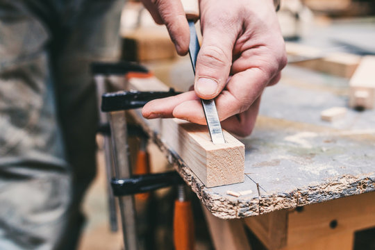 Manual processing of wood in the carpentry workshop - the master works with a chisel