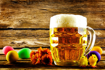 Glass of cold light beer with Easter decorations on a wood background for the Easter holidays