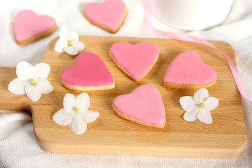 Pretty  girlish flat lay style with gently pink hearts biscuits cookies with white violets blooming flowers and satin ribbon top view.14 february valentine's day gift treat