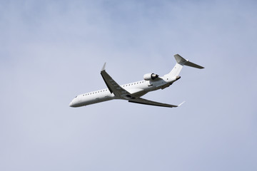 Fototapeta na wymiar White airplane flying in cloudy sky
