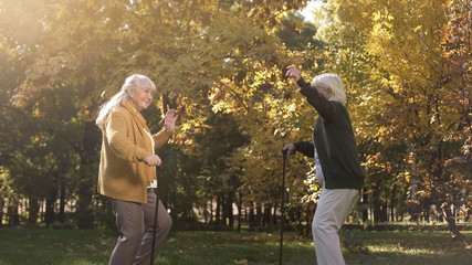 Fototapeta premium Two elder friends dancing and having fun in autumn park, active lifestyle, joy
