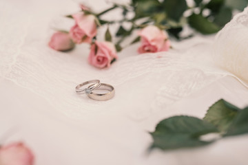 wedding rings and roses bouquet on white tablecloth