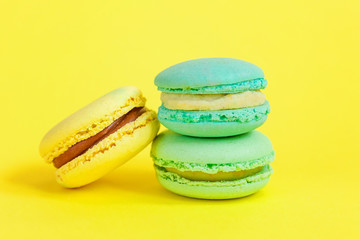 Sweet almond colorful unicorn blue yellow macaron or macaroon dessert cake isolated on trendy yellow modern fashion background. French sweet cookie. Minimal food bakery concept. Copy space