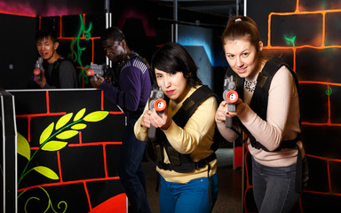 Fototapeta na wymiar two emotional female laser tag players having fun in multinational team