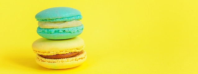 Sweet almond colorful unicorn blue yellow macaron or macaroon dessert cake isolated on trendy yellow modern fashion background. French sweet cookie. Minimal food bakery concept. Copy space