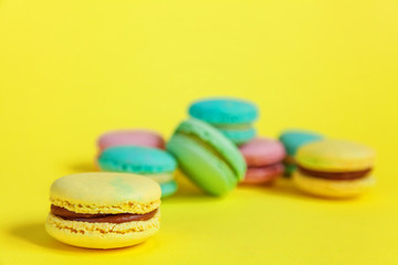 Sweet almond colorful unicorn pink blue yellow green macaron or macaroon dessert cake isolated on trendy yellow modern fashion background. French sweet cookie. Minimal food bakery concept. Copy space
