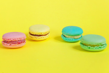 Sweet almond colorful unicorn pink blue yellow green macaron or macaroon dessert cake isolated on trendy yellow modern fashion background. French sweet cookie. Minimal food bakery concept. Copy space