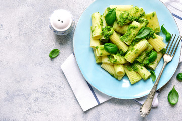 Rigatoni pasta with basil pesto on a blue plate.Top view.