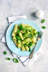 Rigatoni pasta with basil pesto on a blue plate.Top view.