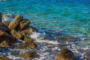 wilderness waterfront stone shoreline and sea vivid blue water waves breaks on rocks local scenic summer landscape view