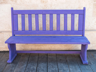 violet colored home made bench on the wooden floor in front of stone house