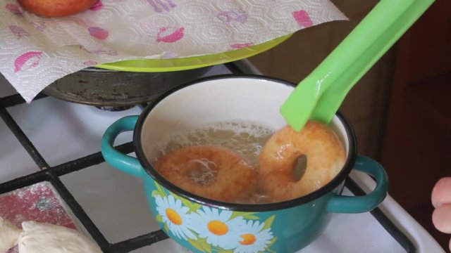 A woman is cooking American donuts. Bake them in sunflower oil...