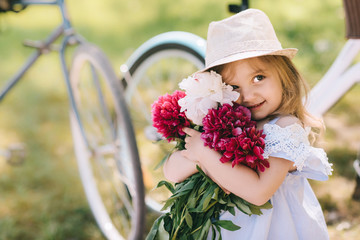 Portrait of a little smiling girl with big bouquet of flowers on te green backgroud