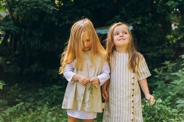 Fototapeta premium two beautiful girls in white antique shirts near a well on a background of grass and trees