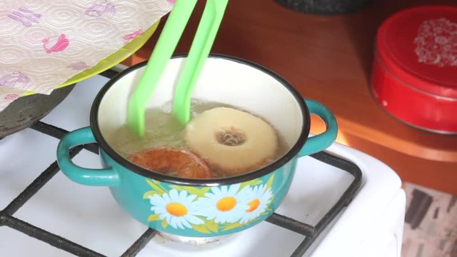 A woman is cooking American donuts. Bake them in sunflower oil.