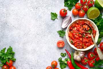 Tomato salsa (salsa roja) - traditional mexican sauce  with ingredients for making on a light grey slate,stone or concrete background.Top view with copy space. - obrazy, fototapety, plakaty