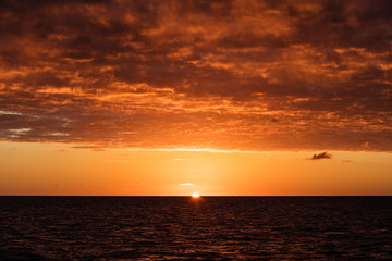 Naklejka na ściany i meble A stunning sunset illuminates clouds drifting above the Caribbean Sea.