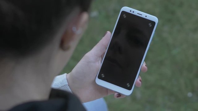 Left-handed woman looking at blank, trackable phone screen, panning shot