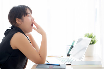 beautiful young freelance asian woman working bored and tired on laptop computer at the office, girl lazy sleepy and yawning on notebook, female secretary with exhausted, business concept.
