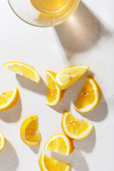Lemons cut into pieces and a glass with natural lemonade on a white background. Top view.
