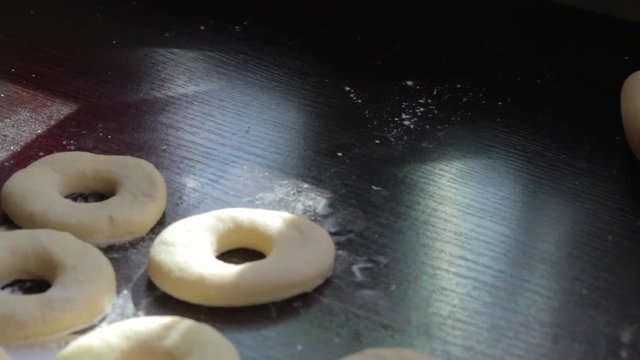 Blanks for American donuts. Made of dough, lie on the surface of the table. Nearby are tools for cooking..