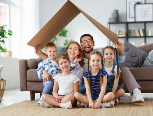 concept of housing and relocation. happy  big family mother father and kids with roof at home .