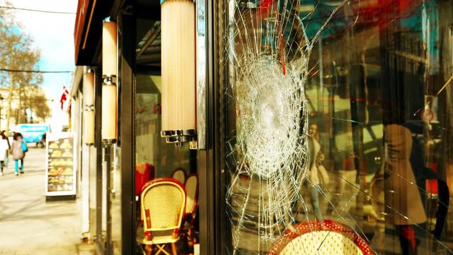 Cinematic grading pedestrians reflected in vandalized glass facade broken of cafe restaurant after demonstrations by the Yellow Vests Gilets Jaunes movement on the Champs-Elysees avenue