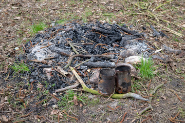 Old rusty cans in a campfire. Place for camping in the forest.