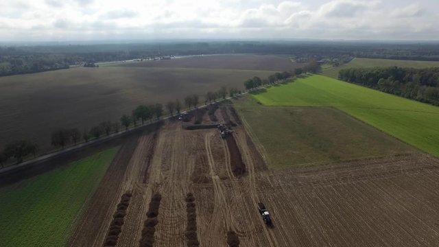 Aerial of excavator loading the tipper truck on an big agriculture field
