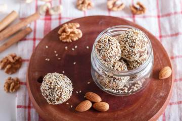 Energy balls cakes with almonds, sesame, cashew, walnuts, dates and germinated wheat in glass jar, side view, close up.