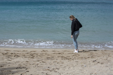 Fototapeta na wymiar Young cute woman walks on sandy beach in spring